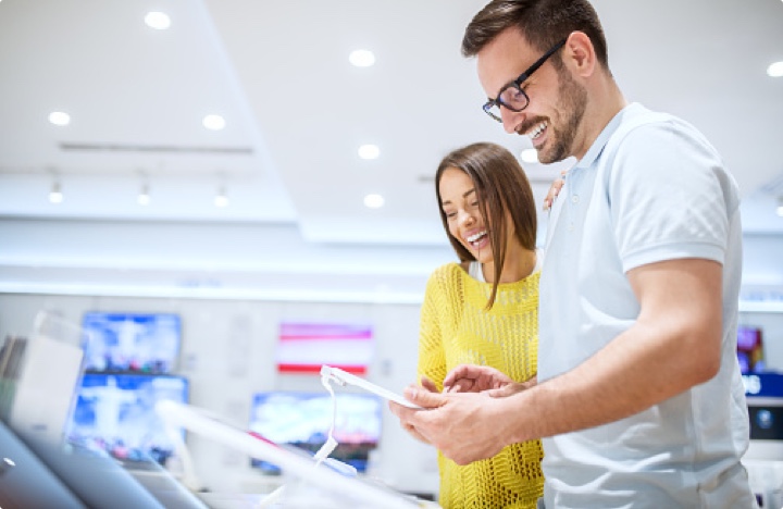 Happy young couple shopping for electronics, TVs and tablets.